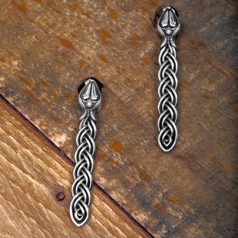 ‘Close-up of elegant earrings in recycled sterling silver, serpent design, the Wise One collection.’