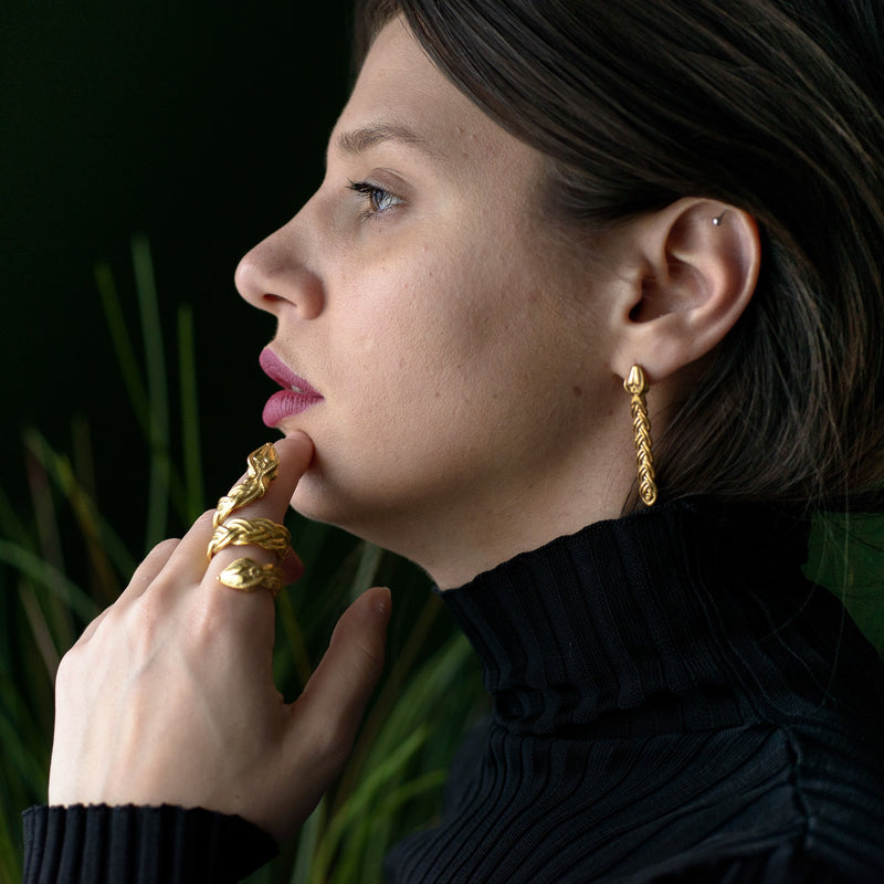 ‘Close-up of elegant earrings in recycled gold, serpent design, the Wise One collection.’