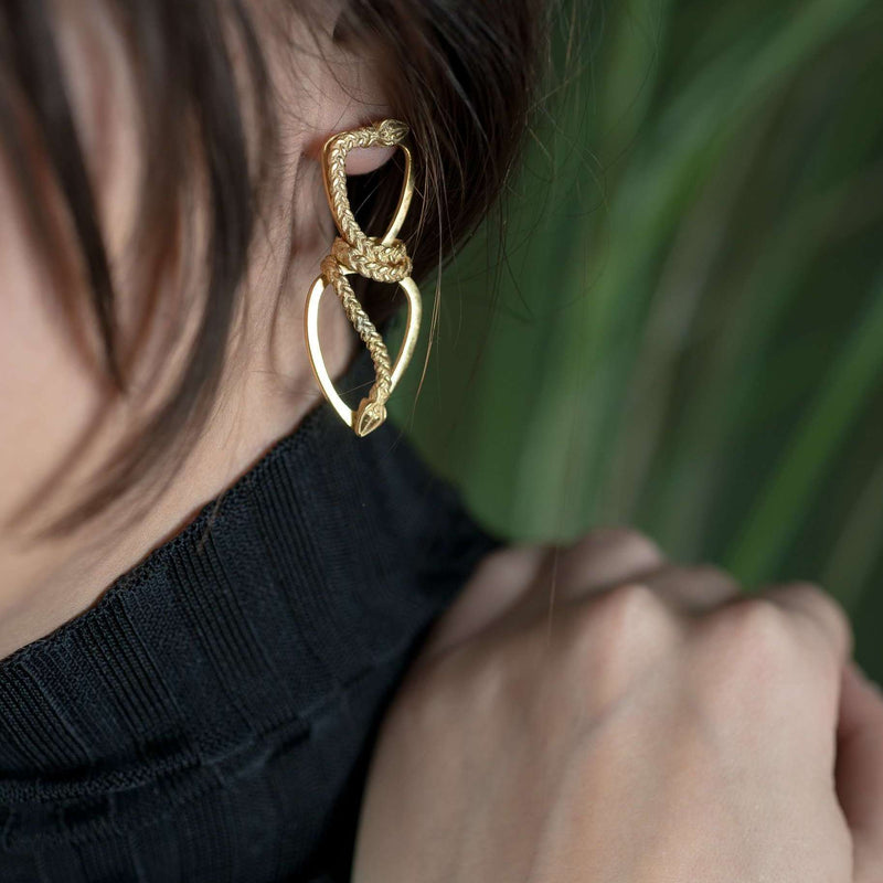 ‘Close-up of Infinity earrings, gold plated, serpent design, the Wise One collection.’